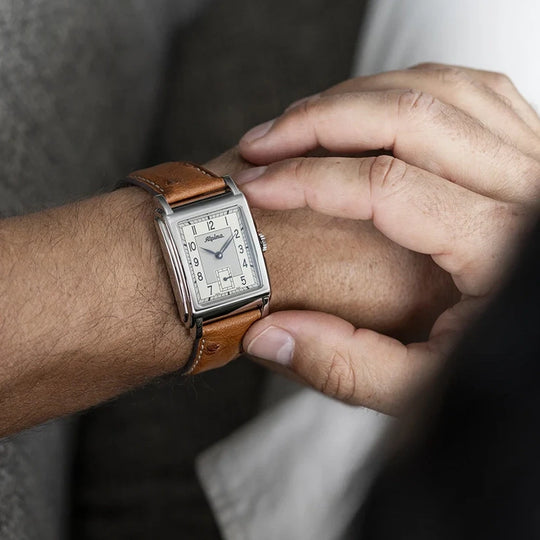 Alpina Heritage Carree Automatic 140 Years rektangulær herreklokke med lys tallskive, kasse i stål og rem av strutseskinn.