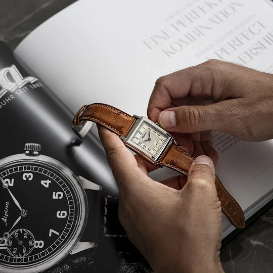 Alpina Heritage Carree Automatic 140 Years rektangulær herreklokke med lys tallskive, kasse i stål og rem av strutseskinn.