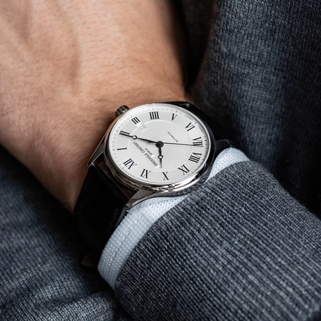 Frederique Constant dressklokke til herre med hvit skive med romertall og sort skinnrem. 50 meter vanntett.