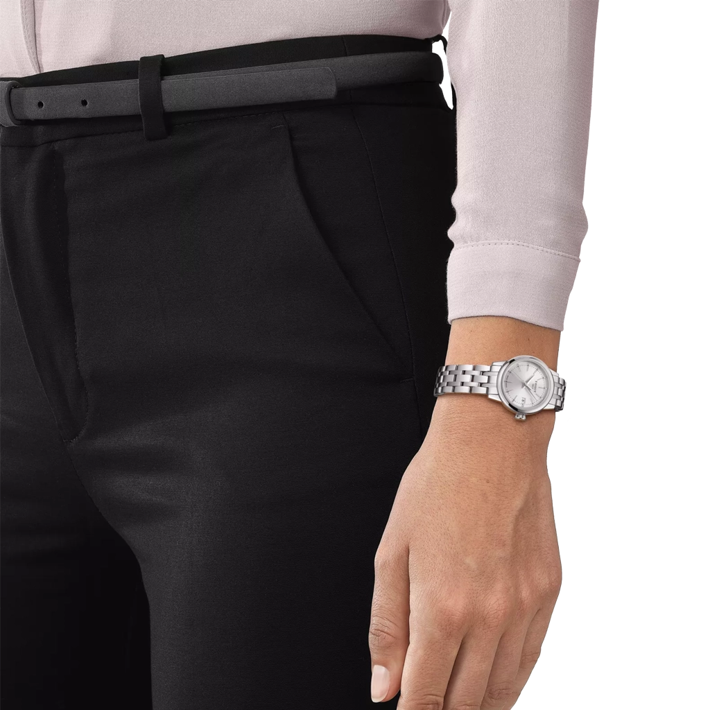 Tissot Classic Dream er en dameklokke på 28 mm. Klokken i stål har en grå tallskive med dato kl 3. Lenken i stål har butterfly clasp. 50 meter vanntett.