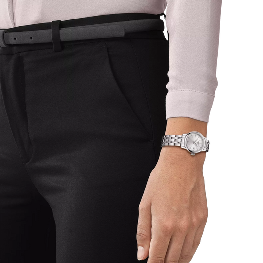 Tissot Classic Dream er en dameklokke på 28 mm. Klokken i stål har en grå tallskive med dato kl 3. Lenken i stål har butterfly clasp. 50 meter vanntett.